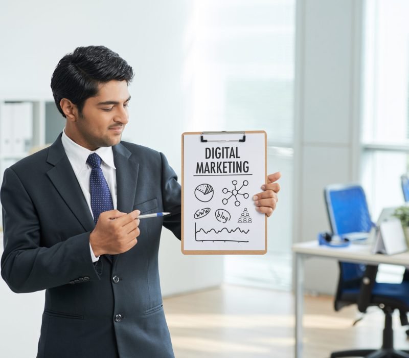 man-suit-standing-office-with-clipboard-pointing-poster-with-words